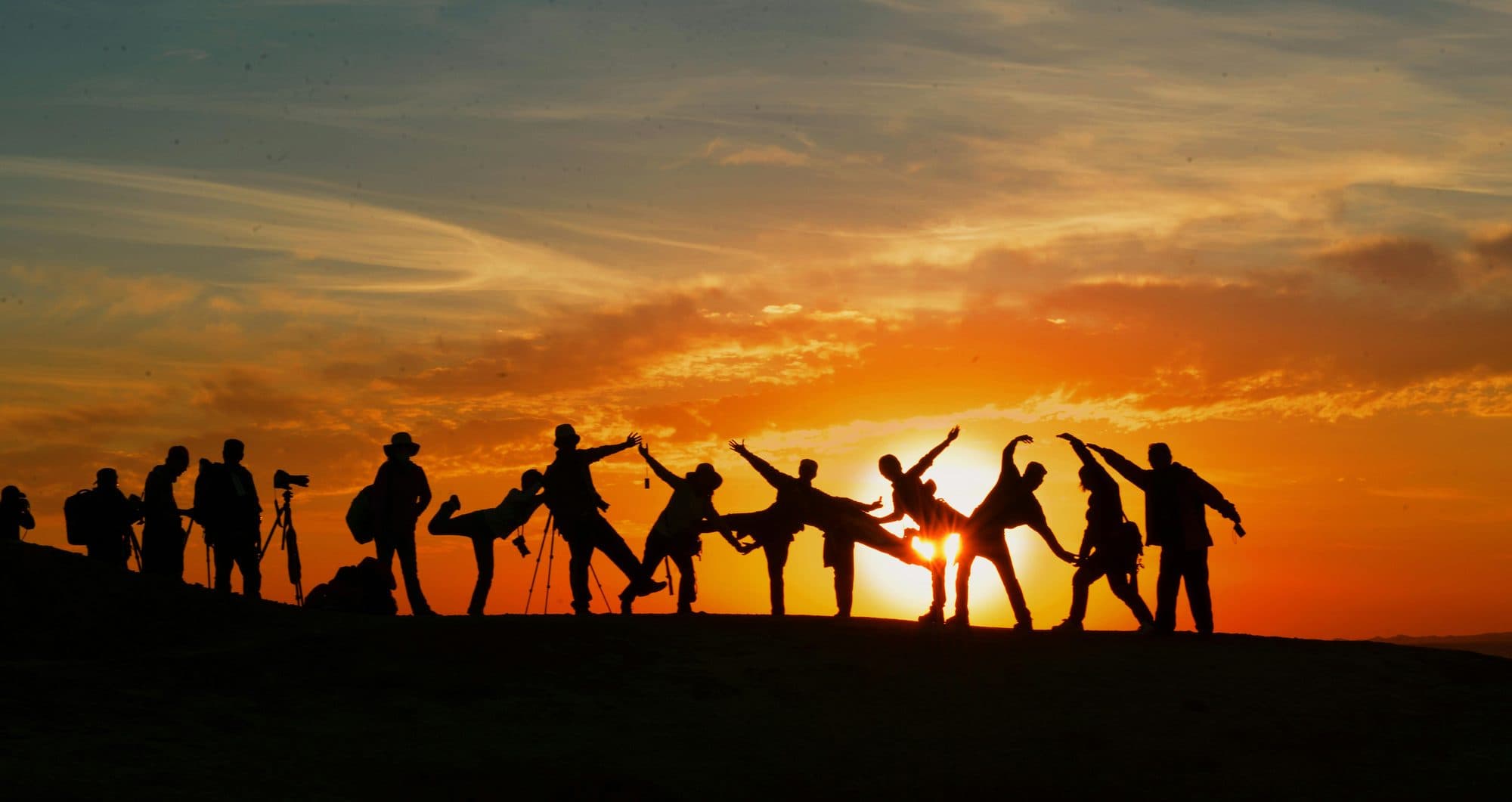 Silhouettes dancing by firelight at dusk