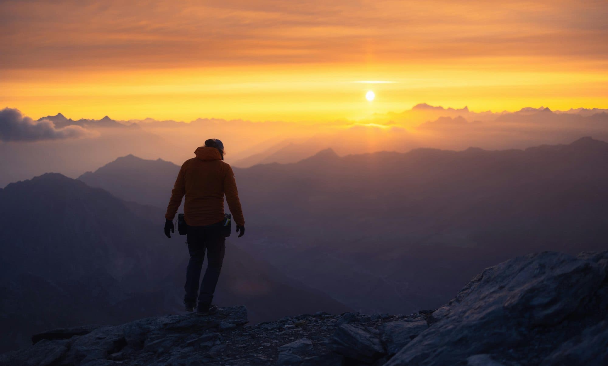 A lone figure on a mountain summit at dusk