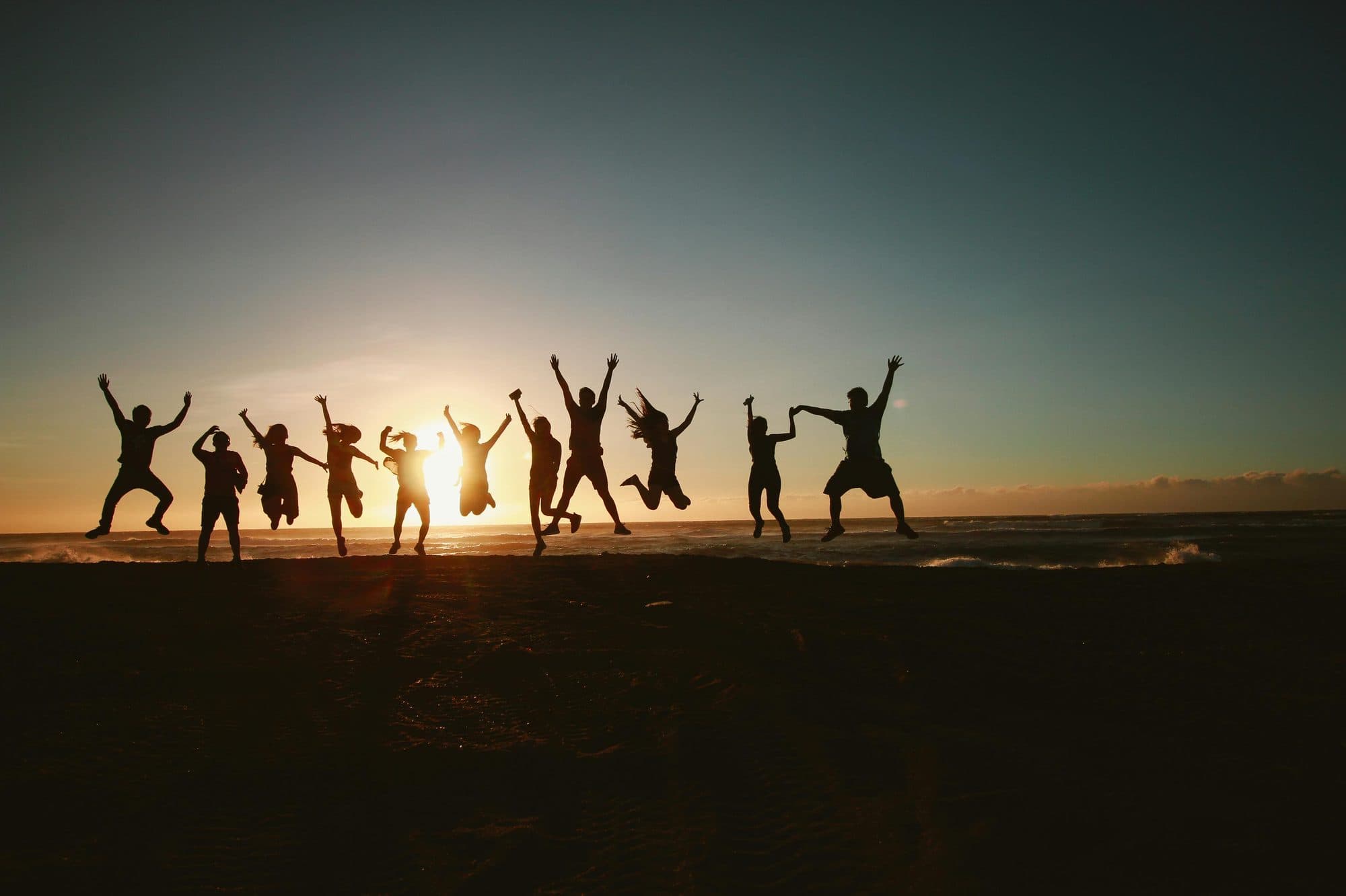 Friends leaping together at sunset