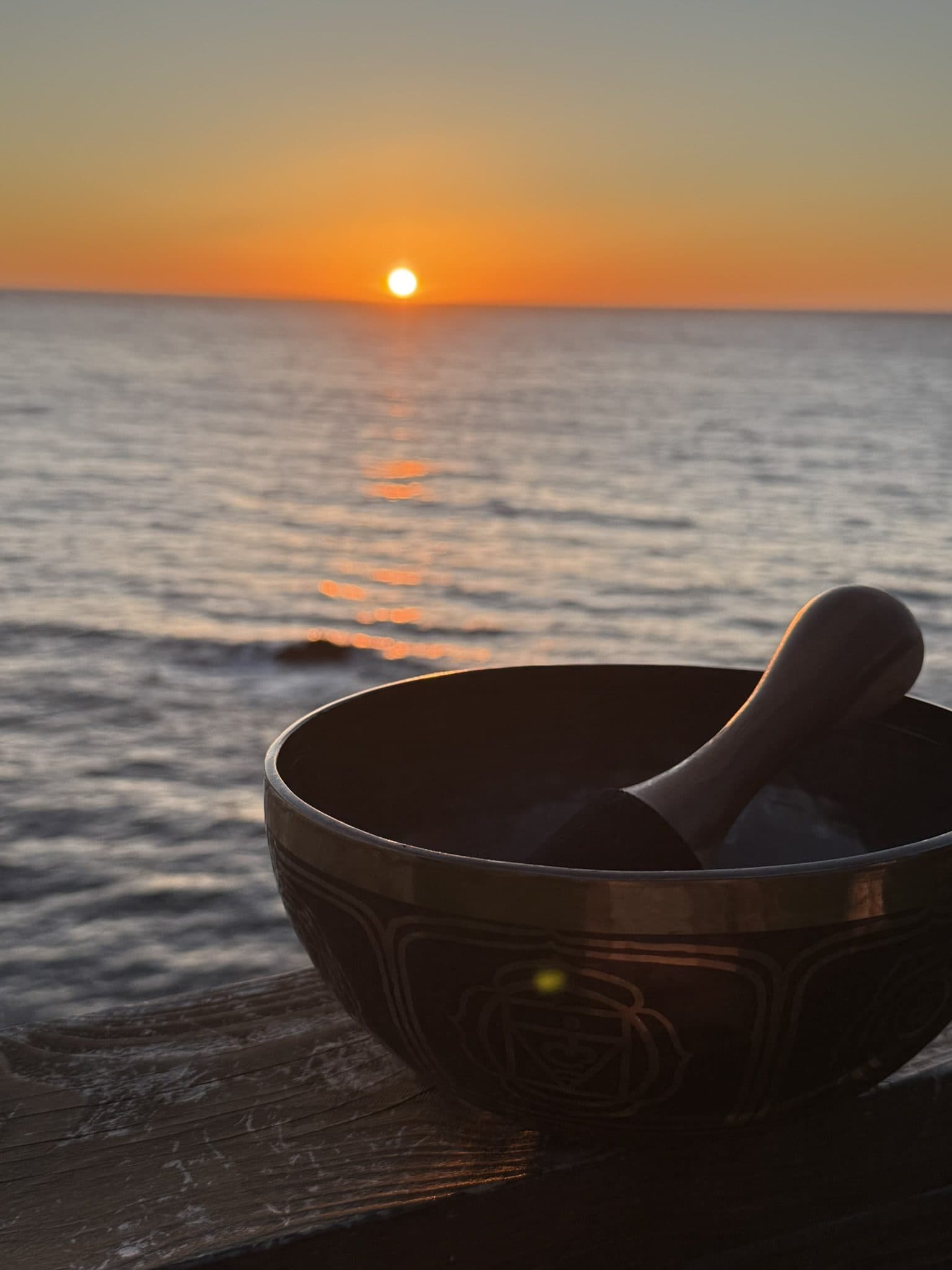 A singing bowl at the water's edge at sunset